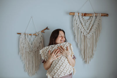 Young girl hugging a macrame covered pillow at home