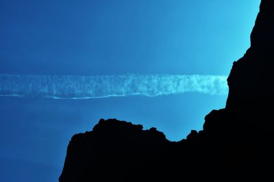 Scenic view of silhouette rocks against clear blue sky