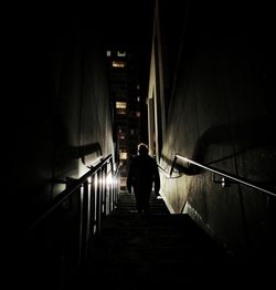 Rear view of silhouette man walking on staircase at night