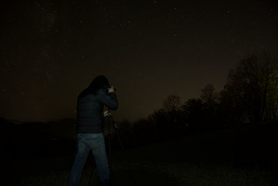 Man photographing against sky at night