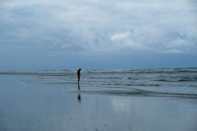 Side view of man standing on shore at beach