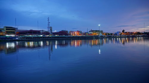 River by illuminated city against sky at dusk