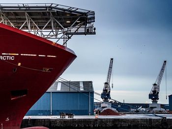 Cropped image of ship moored at commercial dock against sky