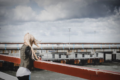 Woman standing on bridge against sky