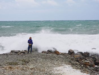 Full length of women standing on rock at beach against sky