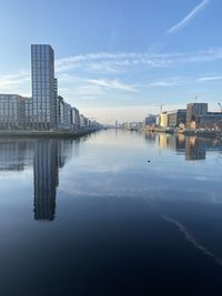 Buildings by river against sky in city