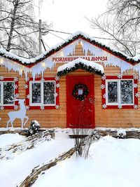 Snow covered house and bare tree against building