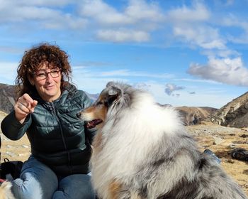 Portrait of woman with dog sitting against sky