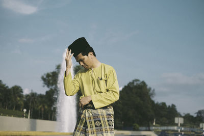 Man in traditional clothing standing against fountain