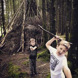 Portrait of boy standing by tree in forest