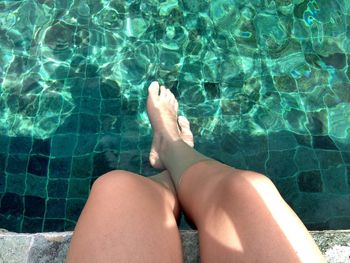 Low section of woman relaxing in swimming pool