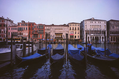 Gondolas moored in canal against buildings