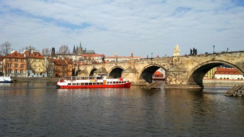 Bridge over river in city against sky