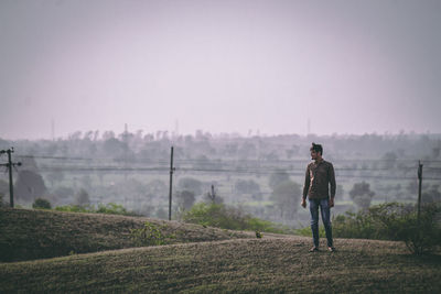 Rear view of man standing on field against sky