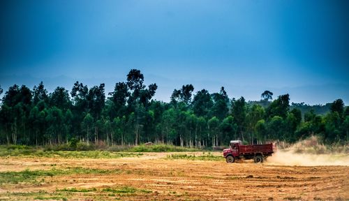 People working on agricultural field against clear sky