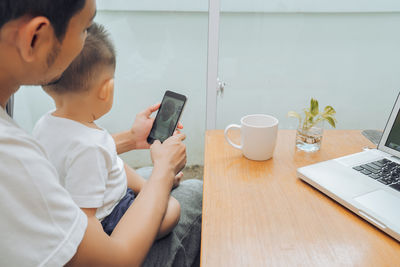 Midsection of woman using mobile phone while sitting on table