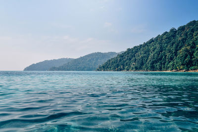 Scenic view of sea by mountains against sky