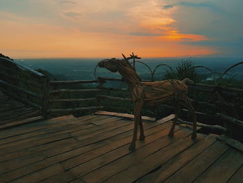 Driftwood on shore by sea against sky during sunset