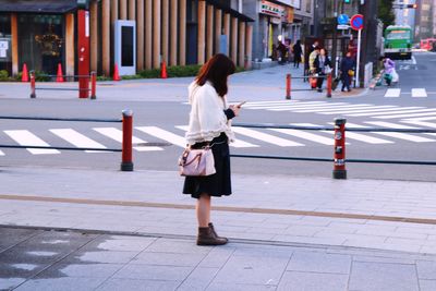 Rear view of woman walking on footpath in city