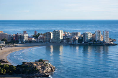 Sea by cityscape against sky