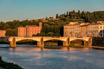 View of ponte alle grazie bridge, river arno and residential area of the city at golden hour.