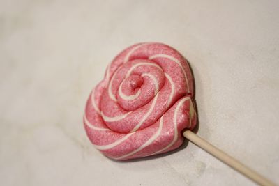 Close-up of pink heart shape lollipop on white table