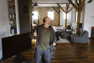 Carefree senior man dancing while listening to music at home