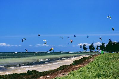 People kiteboarding in sea against blue sky