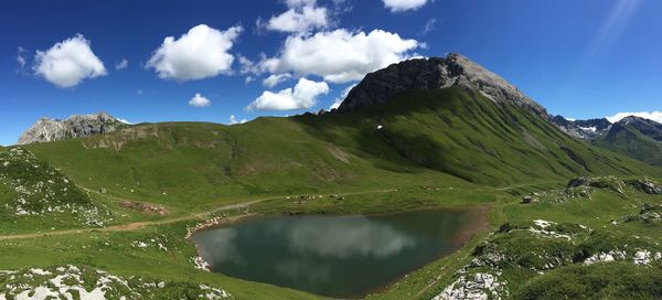 Scenic view of mountain by pond against sky