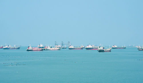 Boats in sea against clear blue sky