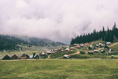 Panoramic view of houses and trees on field against sky