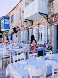 Rear view of woman sitting on table against buildings in city