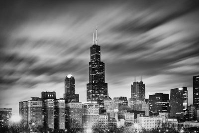 Low angle view of illuminated city against cloudy sky