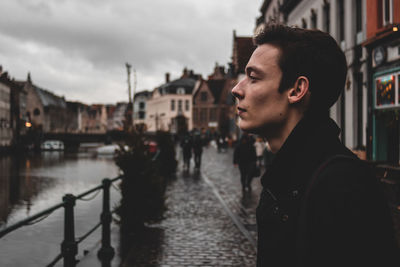 Side view of man standing by railing in city