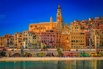 Buildings by river against sky