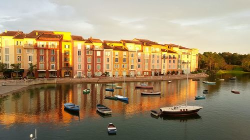 Boats moored in river by city against sky