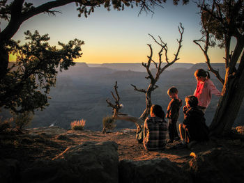 Family on hill against sky during sunset