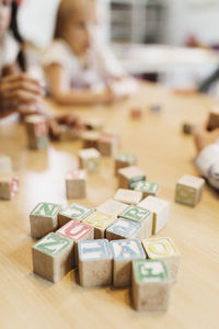 Alphabet blocks on table with children sitting in background