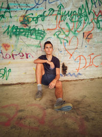 Portrait of young man sitting on wall