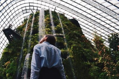 Rear view of man and woman standing in greenhouse