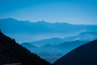 Scenic view of silhouette mountains against clear blue sky