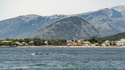 Scenic view of sea by buildings against mountains