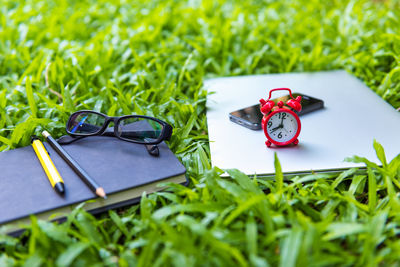 Close-up of eyeglasses with book and mobile phone on grassy field