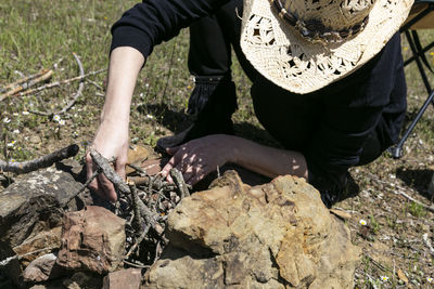 High angle view of woman arranging firewood on field during sunny day