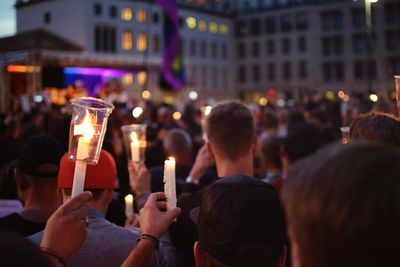 Crowd holding candles during homage in city at dusk