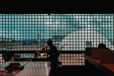 Man reading book by glass window