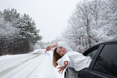 Woman lying outside car window during winter
