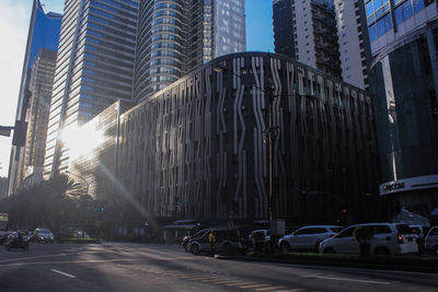 City street by modern buildings against sky