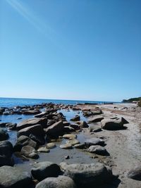 Rocks on beach against clear blue sky