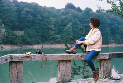 Side view of woman sitting on railing